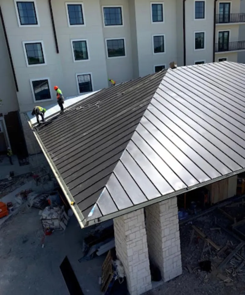 Crew installing standing seam metal roof panels on a commercial project in Osage Beach